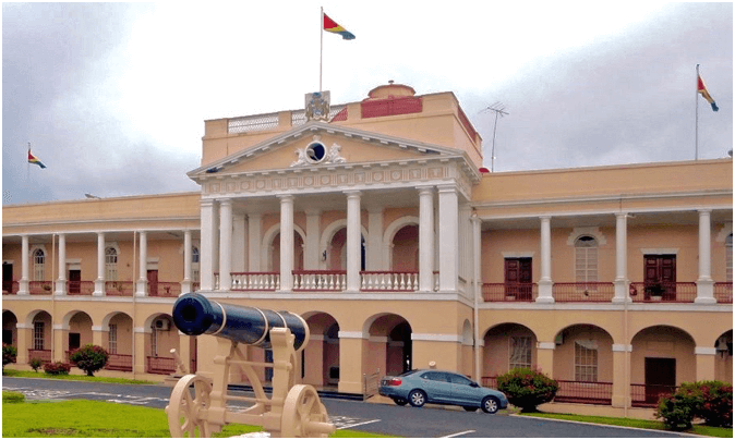 Salmon brick neo-Classical Parliament Building in Georgetown, Guyana, with cannon on the lawn
